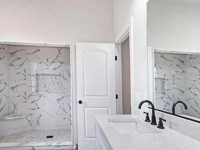 Walk-in shower with large-format marble tile, built-in niche, and double vanity with mirror in Broomall, PA
