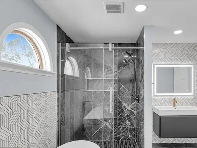 Custom bathroom remodel with dark marble shower, geometric tile accent walls, and floating vanity in Bryn Mawr, PA