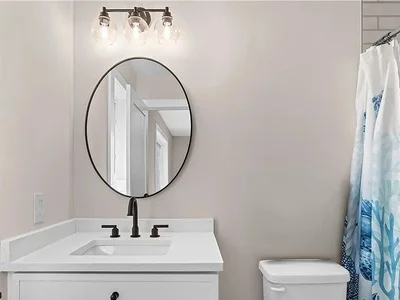 Remodeled bathroom vanity with oval mirror, globe light fixture, and clean white cabinetry in Gladwyne, PA