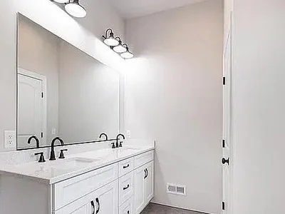 Double vanity with white cabinetry, large frameless mirror, and dual light fixtures in Paoli, PA