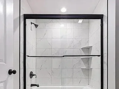 Tub and shower combo with sliding glass door and white marble subway tile in Strafford, PA