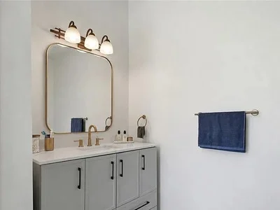 Powder room vanity with gray cabinetry, gold fixtures, and soft overhead lighting in Strafford, PA